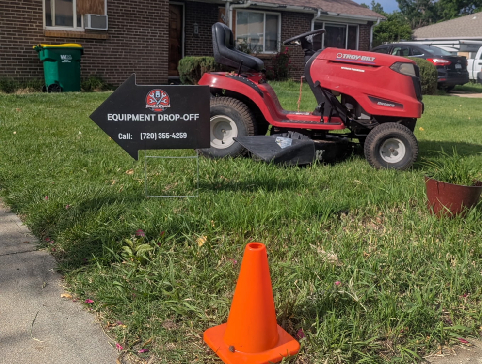 Equipment drop-off sign in front of a riding mower awaiting service