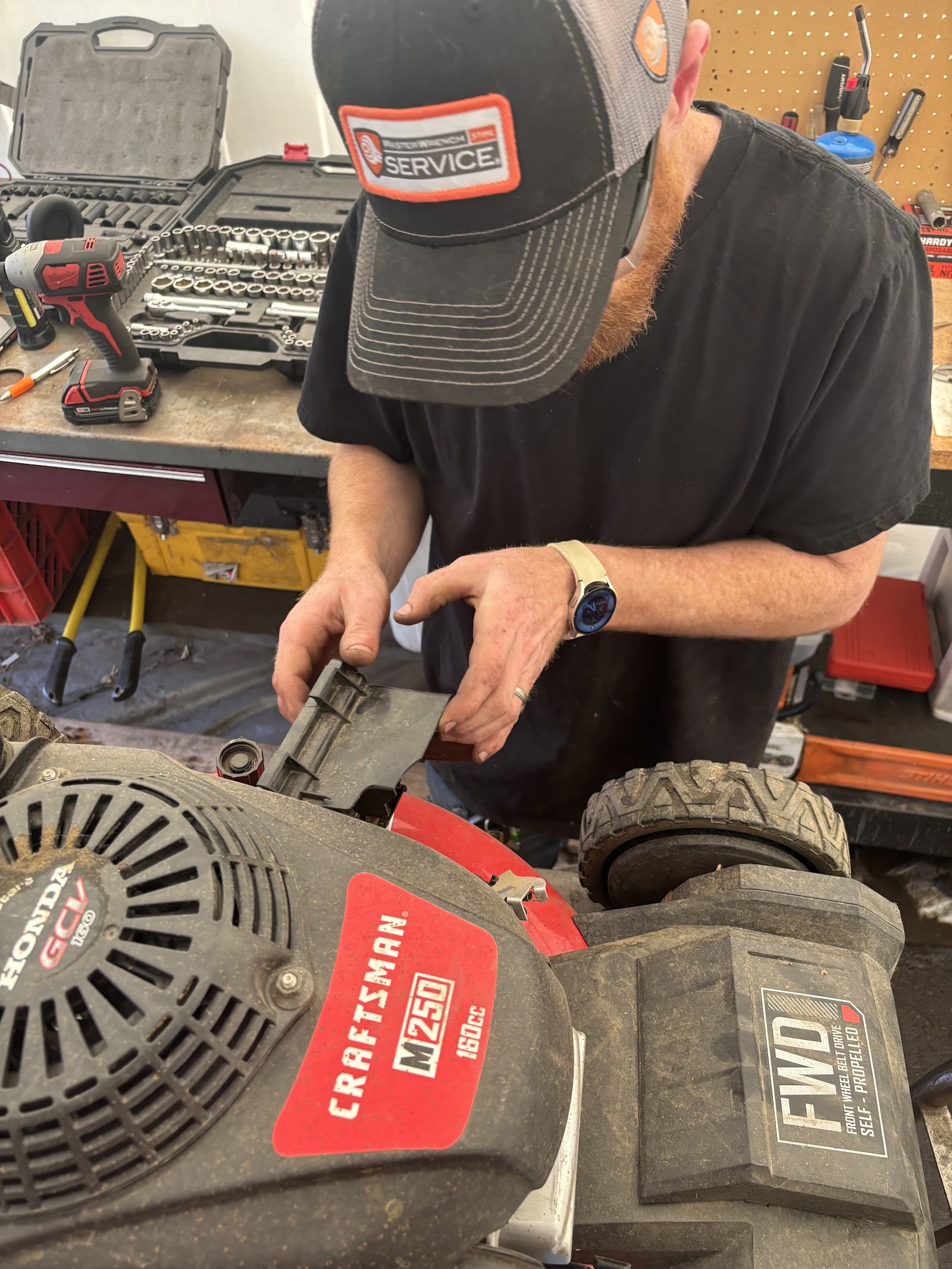 Rebuilding a Craftsman mower engine at the workbench, socket sets on the pegboard